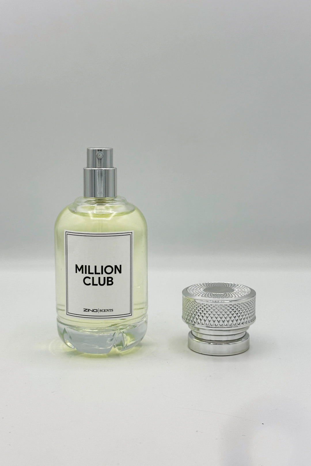 Million club perfume bottle with its silver textured lid placed beside the perfume bottle displayed on a white background.